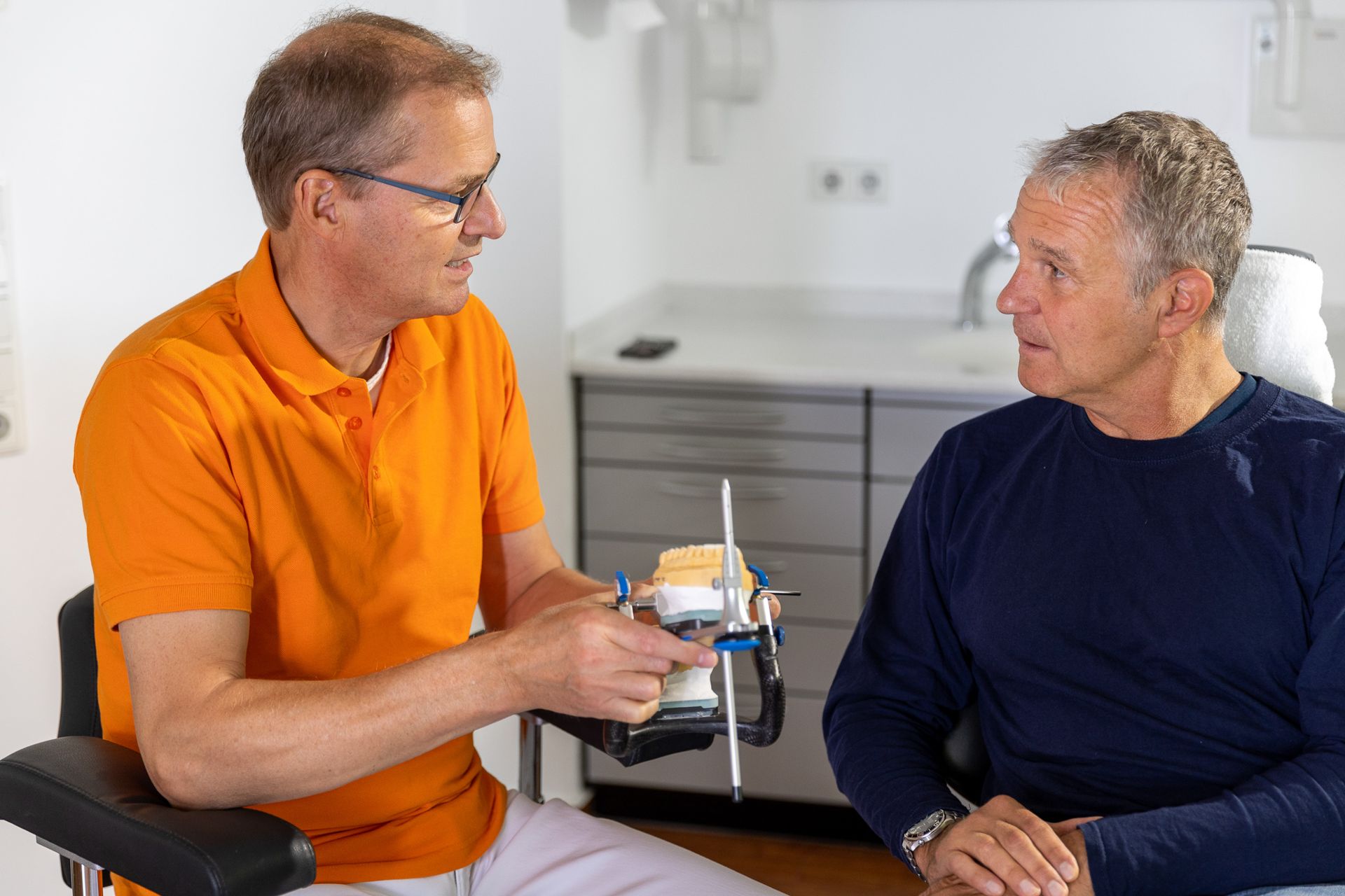 Dr. Arnd Schmitt erklärt einem Patienten die Funktionsanalyse am Artikulator