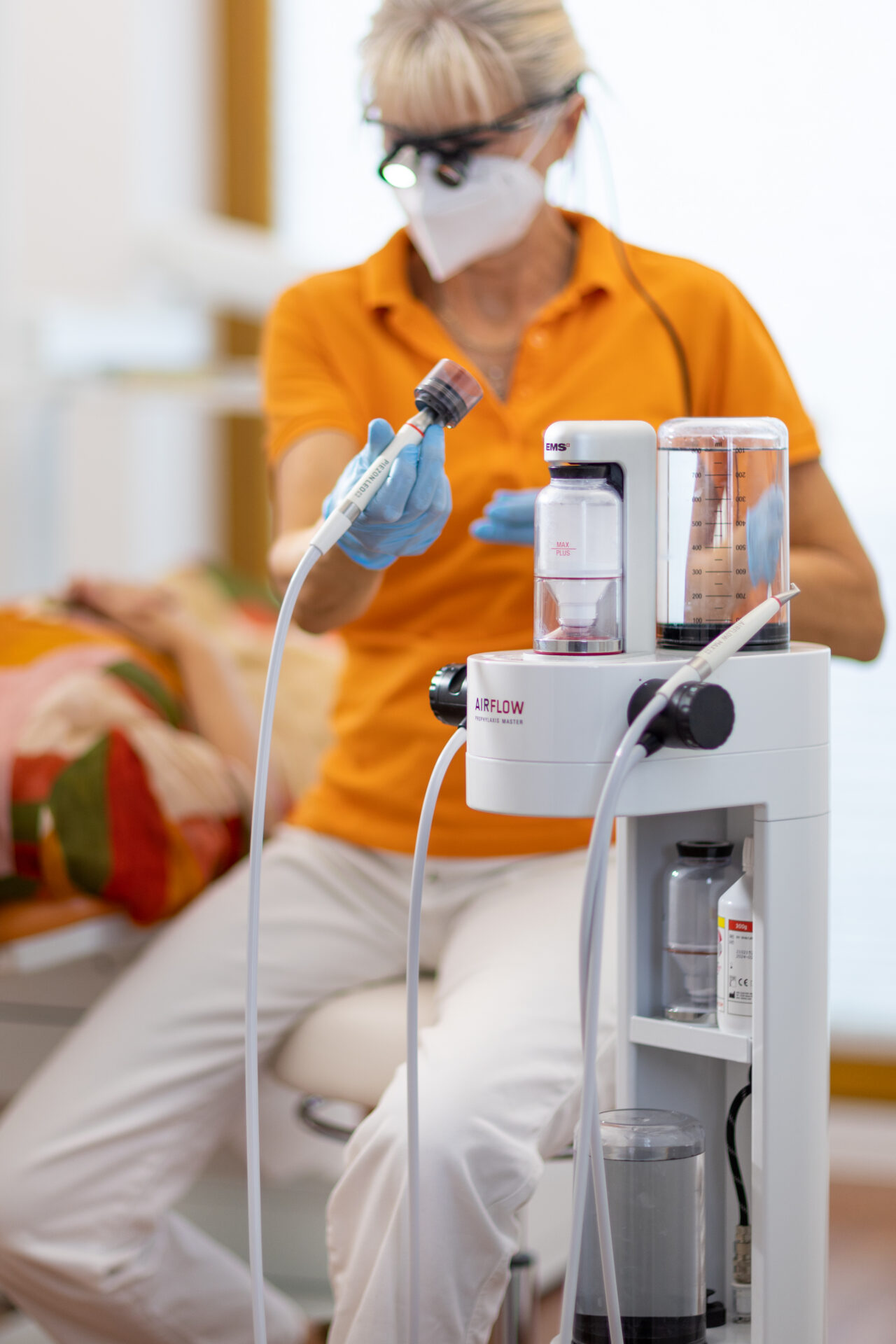 Prophylaxe-Mitarbeiterin mit dem Airflow-Gerät für die Zahnreinigung