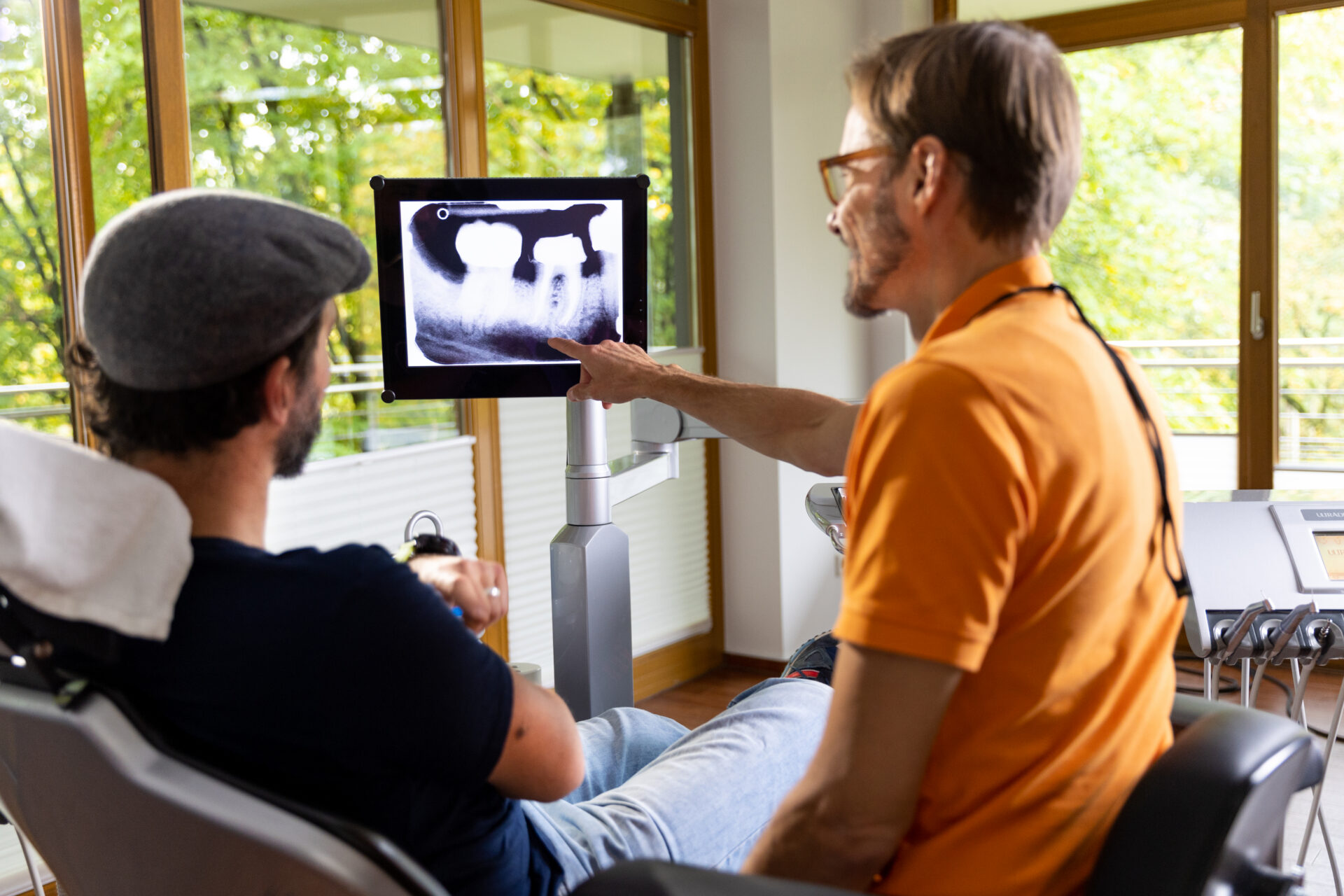 Röntgenaufnahme eines Zahns wird dem Patienten am Bildschirm erklärt