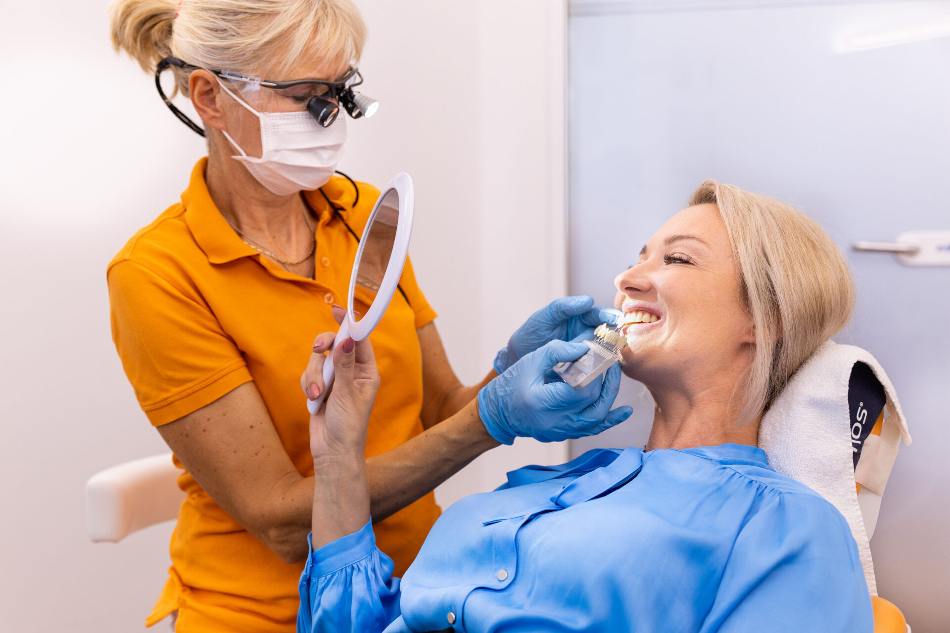 Zufriedene Patientin mit Handspiegel nach der Behandlung
